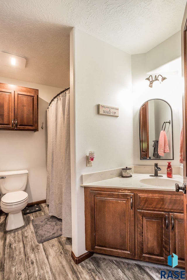 bathroom featuring vanity, a textured ceiling, hardwood / wood-style flooring, and toilet