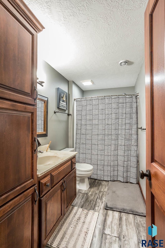 bathroom featuring vanity, hardwood / wood-style floors, a textured ceiling, and toilet