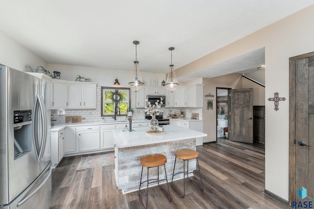 kitchen with white cabinetry, dark hardwood / wood-style floors, pendant lighting, a kitchen island, and appliances with stainless steel finishes