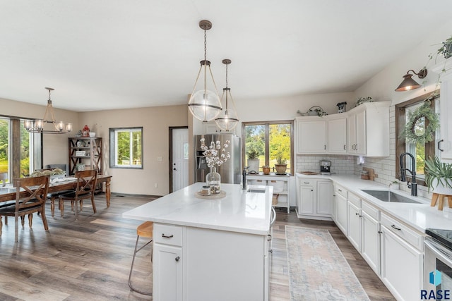 kitchen featuring sink, decorative backsplash, stainless steel fridge, decorative light fixtures, and a kitchen island