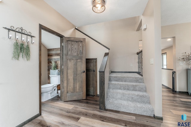 staircase featuring a textured ceiling and hardwood / wood-style flooring