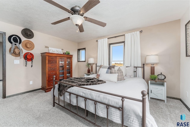 carpeted bedroom featuring ceiling fan and a textured ceiling