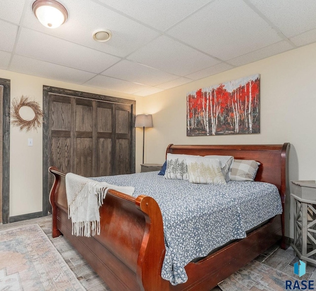 bedroom with wood-type flooring and a drop ceiling