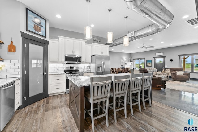 kitchen with white cabinetry, ceiling fan, light stone counters, and appliances with stainless steel finishes