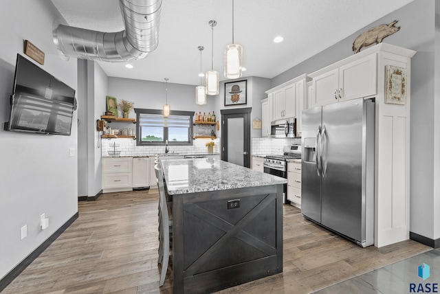 kitchen featuring white cabinets, decorative backsplash, decorative light fixtures, a kitchen island, and stainless steel appliances