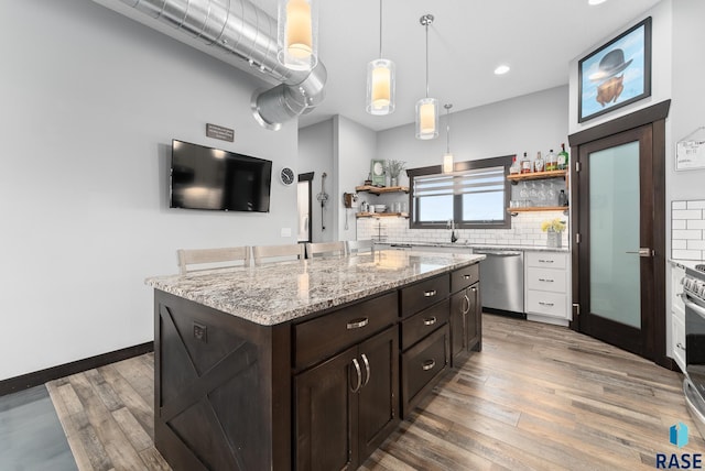 kitchen with dark brown cabinetry, hanging light fixtures, stainless steel appliances, decorative backsplash, and a kitchen island