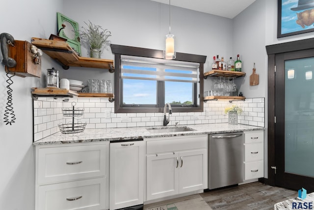 kitchen featuring dark wood-type flooring, white cabinets, sink, stainless steel dishwasher, and light stone counters