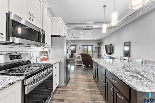 kitchen featuring appliances with stainless steel finishes, ceiling fan, pendant lighting, hardwood / wood-style floors, and white cabinetry