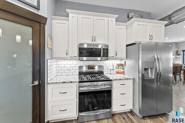 kitchen featuring white cabinets, decorative backsplash, light stone countertops, and appliances with stainless steel finishes