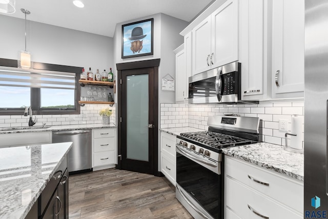 kitchen featuring dark hardwood / wood-style flooring, stainless steel appliances, sink, white cabinetry, and hanging light fixtures