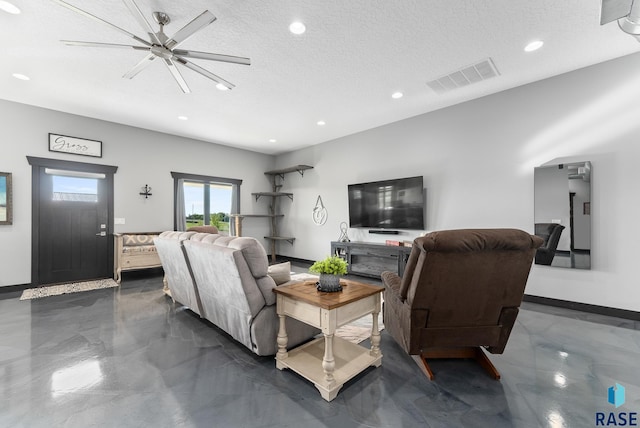 living room with ceiling fan and a textured ceiling