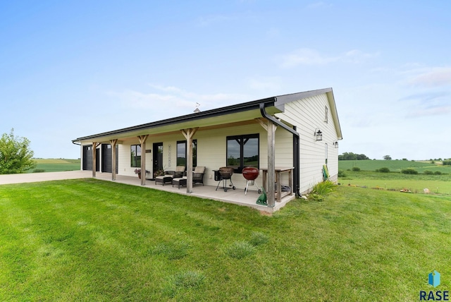 back of property with outdoor lounge area, a yard, a rural view, and a patio area