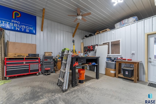 garage with a workshop area, ceiling fan, and wood walls