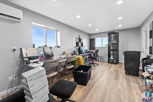 office space featuring an AC wall unit, light hardwood / wood-style flooring, and a textured ceiling