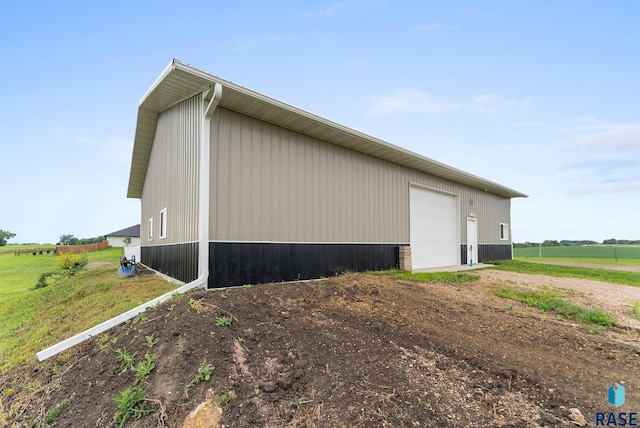 view of side of property with a garage, a rural view, and an outdoor structure