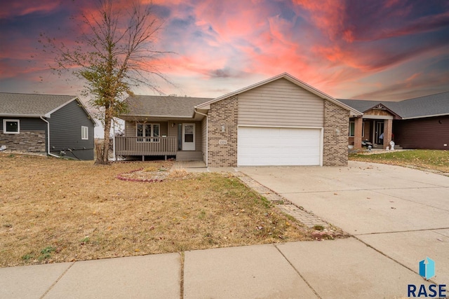 single story home with a porch, a garage, and a yard