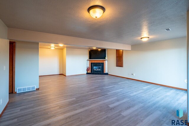 unfurnished living room featuring a textured ceiling, wood-type flooring, and a fireplace