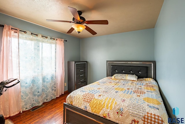 bedroom featuring ceiling fan, dark hardwood / wood-style flooring, and a textured ceiling