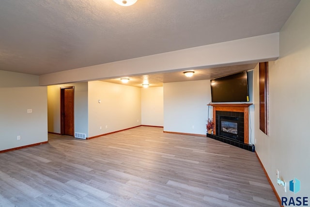 basement featuring a tile fireplace and light hardwood / wood-style floors