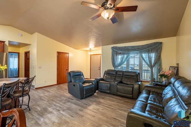 living room featuring ceiling fan, hardwood / wood-style floors, and vaulted ceiling