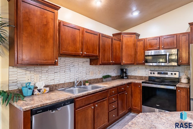 kitchen with decorative backsplash, sink, vaulted ceiling, and appliances with stainless steel finishes