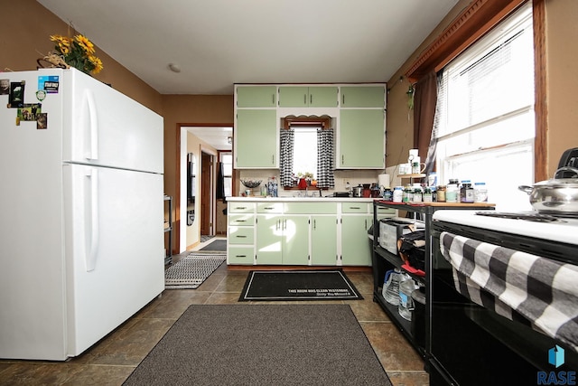 kitchen featuring black range with electric cooktop, white fridge, green cabinetry, and sink