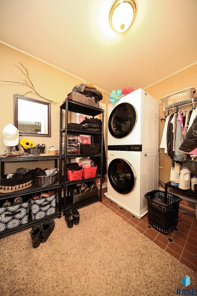 laundry area featuring stacked washer and dryer and dark tile patterned flooring