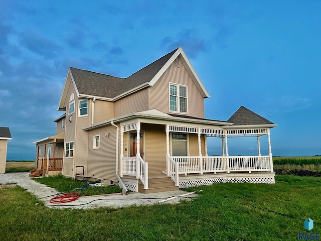 back of property featuring a yard and covered porch