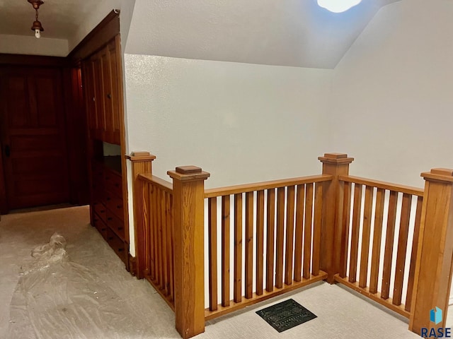 hallway with light carpet and lofted ceiling