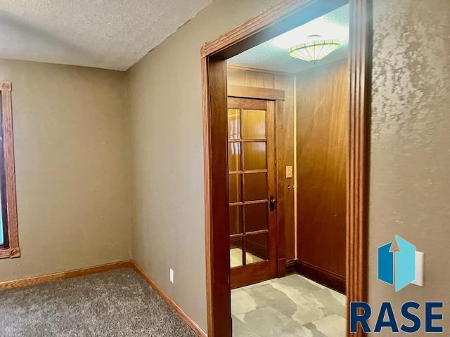 hall featuring carpet flooring and a textured ceiling