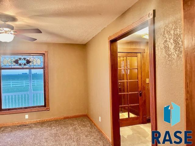 spare room with ceiling fan, light colored carpet, and a textured ceiling