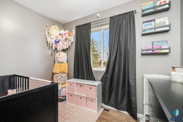 bedroom featuring light hardwood / wood-style flooring and a nursery area