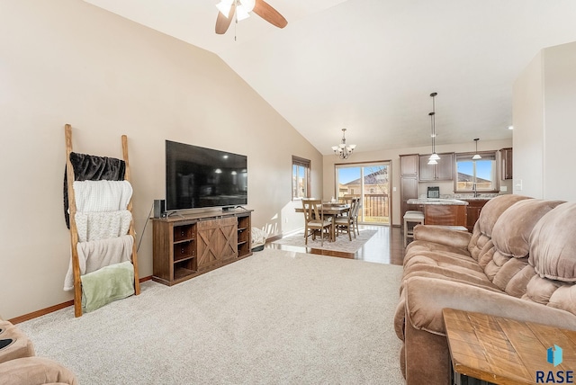 living room featuring carpet, ceiling fan with notable chandelier, lofted ceiling, and sink