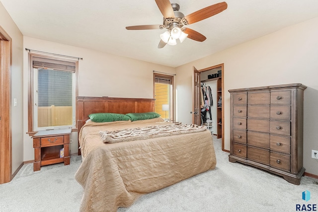 bedroom featuring ceiling fan, wood walls, light colored carpet, and a closet