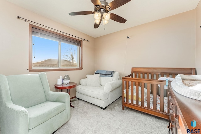 bedroom featuring light carpet, a nursery area, and ceiling fan