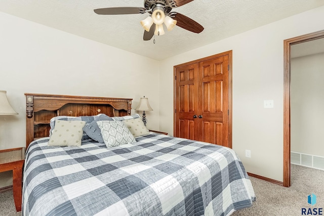 carpeted bedroom with ceiling fan, a closet, and a textured ceiling