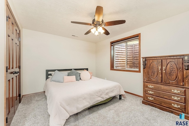 bedroom featuring ceiling fan, a closet, light colored carpet, and a textured ceiling