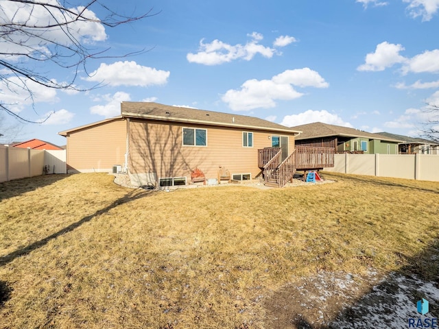 rear view of house with a wooden deck and a yard