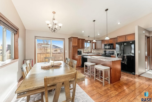 dining area featuring light hardwood / wood-style floors, vaulted ceiling, a notable chandelier, and sink