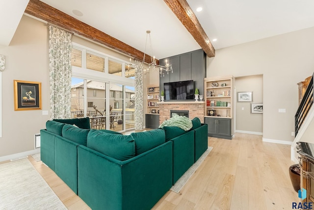 living area featuring baseboards, light wood-style floors, beam ceiling, a brick fireplace, and a notable chandelier