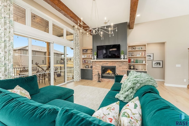 living area with a notable chandelier, wood finished floors, baseboards, a brick fireplace, and beam ceiling