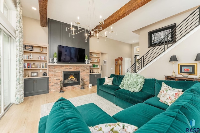 living area with light wood-style floors, a brick fireplace, beam ceiling, and stairs