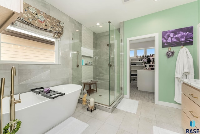 full bath featuring a freestanding tub, vanity, a spacious closet, a shower stall, and tile patterned floors