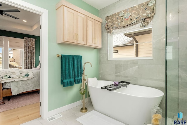 ensuite bathroom with a freestanding tub, visible vents, baseboards, a ceiling fan, and ensuite bath