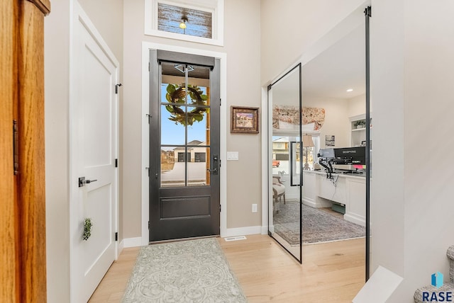 entrance foyer with baseboards, visible vents, and light wood finished floors