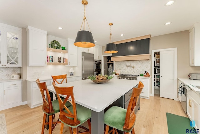 kitchen with high end appliances, light countertops, white cabinets, and hanging light fixtures