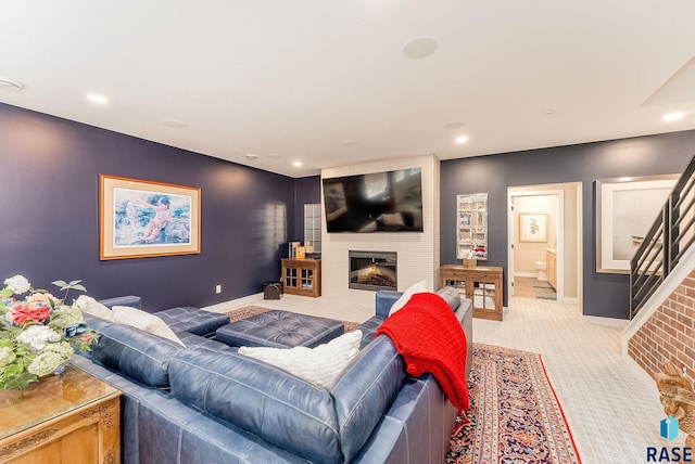 living room with light carpet, a large fireplace, stairs, and baseboards