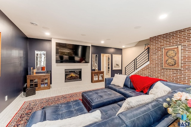 carpeted living area with recessed lighting, a fireplace, stairway, and brick wall