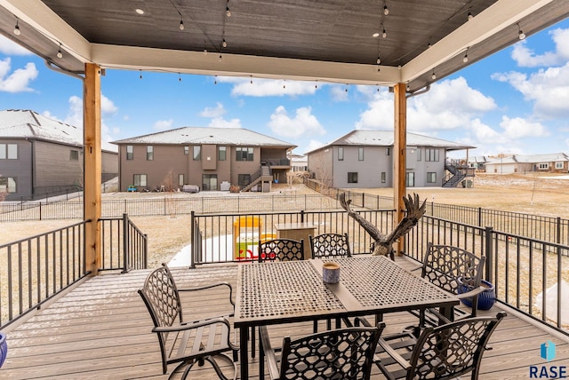 wooden deck with a residential view, fence, and outdoor dining space