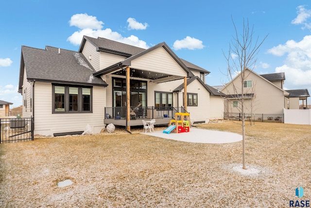 back of house with a shingled roof, a patio, a deck, and fence